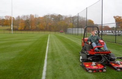 Rotary mower mowing on athletic field.